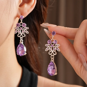 Detail of silver drop earrings with round and pear-cut purple crystals on model