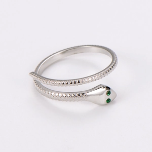 Detailed macro view of silver snake ring featuring green gem eyes and scale texture