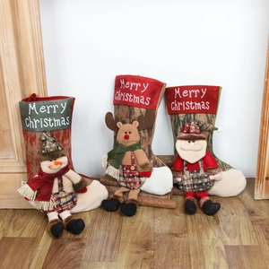 Three Christmas stockings with snowman, reindeer, and Santa Claus patterns on wooden floor