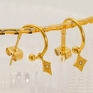 Close-up of gold star earrings with sparkling rhinestones on a glass rim background