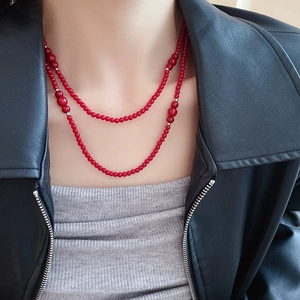 Detail view of double-layered red beaded necklace styled with a black leather jacket