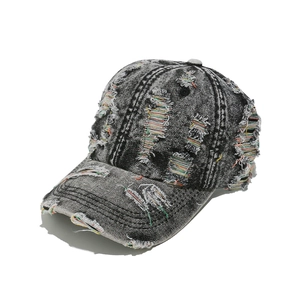 Détail de la casquette en denim délavé avec trous vintage usés et surpiqûres colorées