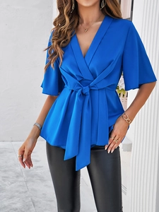 Détail du haut bleu élégant à col en V avec ceinture et manches fluides sur modèle