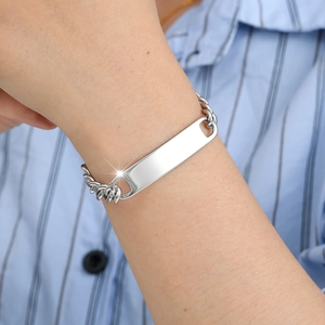 Close-up of a polished stainless steel Cuban chain bracelet with a blank ID plate on wrist