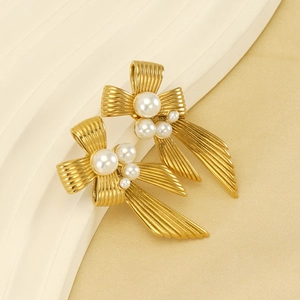 Detailed macro view of vintage gold bow earrings with elegant white pearls and silk background