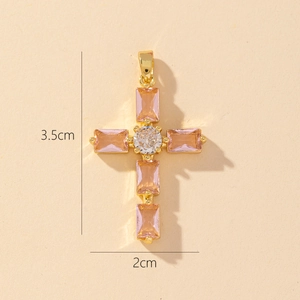 Detailed size view of gold cross pendant with pink gemstones measuring 3.5cm by 2cm