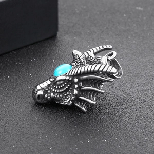 Macro detail of punk dragon head pendant in vintage steel with inlaid blue stone