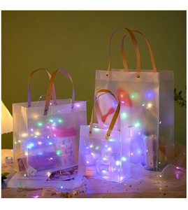Frosted gift bags in three sizes with brown handles and glowing colorful LED light strings