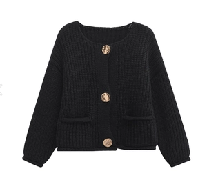 Detail of black chunky knit cardigan featuring textured golden buttons and round neck