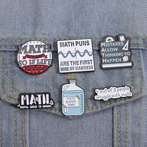 Set of six metal math formula enamel pins displayed on blue denim pocket fabric