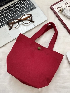Minimalist burgundy canvas tote bag with metal snap button and laptop workspace items