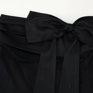 Women's autumn mini skirt in black featuring a large satin bow and delicate lace patchwork