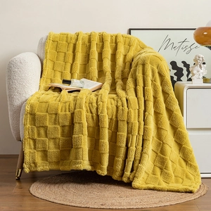 Close-up of mustard yellow thick checkered blanket draped over a white fabric sofa