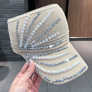 Detail eines beigen Strick-Sonnenvisiers mit weißen Perlen und glitzernden Strasssteinen