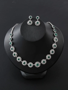 Detail of emerald green jewelry set with necklace and earrings on a black display