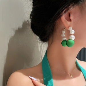 Retro hoop earrings with white pearls and green flocked beads on a female model