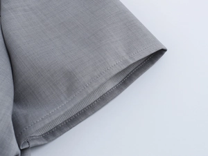 Gros plan du revers de manche courte grise avec double couture nette et tissu texturé
