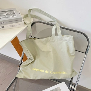 Detail of light green canvas tote bag with Magasin de Croissants text on a chair