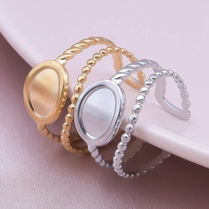 Detailed view of four geometric gold and silver stainless steel rings on a ceramic plate