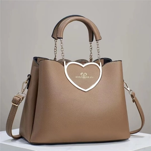 Macro detail of khaki leather handbag with 'always love you' heart buckle and chain handle