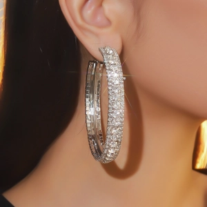 Primo piano dell'orecchino a cerchio argentato con strass scintillanti su modella
