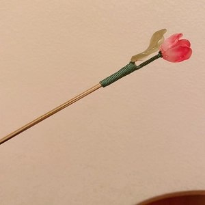 Detail of tulip hair pin with pink glass petals and gold metal stem with thread wrap