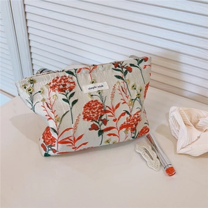 Detail of red floral embroidery and 'simple wish' label on beige canvas makeup bag