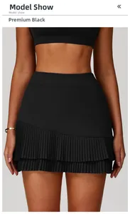 Detail of high-waisted black pleated tennis skirt featuring a double-layered asymmetric hem