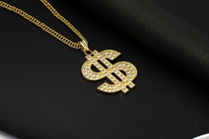 Close-up of a gold-plated dollar sign hip-hop pendant encrusted with sparkling crystals