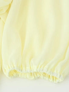 Close-up of pleated chiffon long sleeve cuffs with elastic frill detail in pale yellow