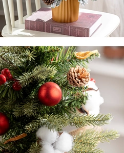 Close-up of a mini Christmas tree with pine cones, cotton, and red berries in a gold pot