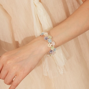 Close-up of pastel enamel flower charm bracelet with colorful daisy petal details