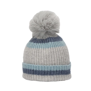 Détail du tricot côtelé épais et pompon en fausse fourrure douce sur le bonnet rayé bleu