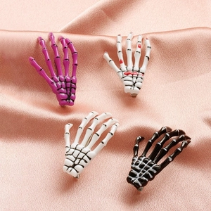 Gothic skull hand hair clips in black, white, and purple on pink satin background