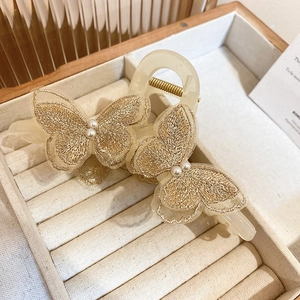 Detailed close-up of butterfly hair claw clip with golden embroidery and pearl accents