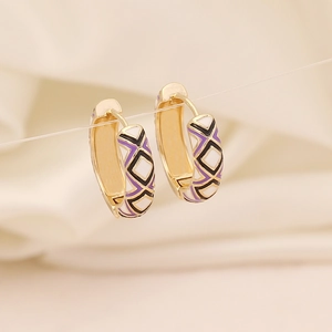 Détail de boucles d'oreilles losanges dorées avec émail violet, noir et blanc