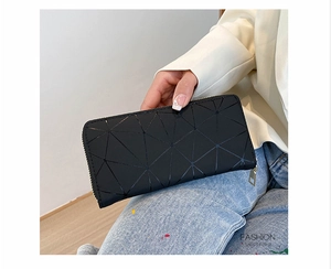 Macro shot of black long wallet with geometric triangular texture and gold zipper detail