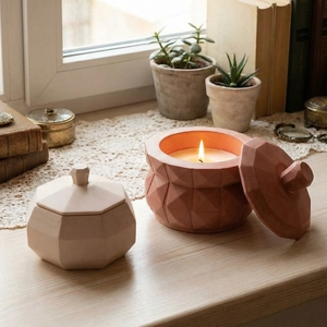 Detailed view of geometric resin candle cups with lids in beige and terracotta tones