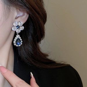 Close-up of sparkling floral earrings with white and blue cubic zirconia crystals