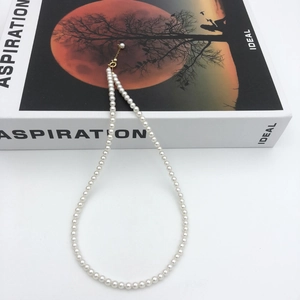 Detail of white pearl necklace with gold-plated adjustable clasp on minimalist book