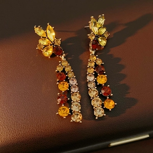 Detail von Vintage-Goldohrringen mit bernsteinfarbenen Kristallen auf braunem Leder