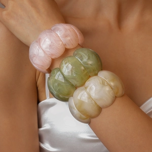 Close-up of pink, green and beige acrylic marbled bangles stacked on a female wrist