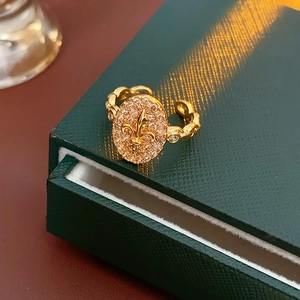Bague iris dorée avec cristaux sur écrin de luxe vert, vue détaillée élégante