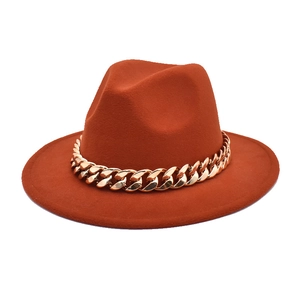 Detailed close-up of the vintage rust wool fedora hat with a bold gold chain decoration