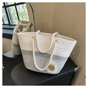 Detailed close-up of beige woven tote bag featuring daisy decor and rope handles