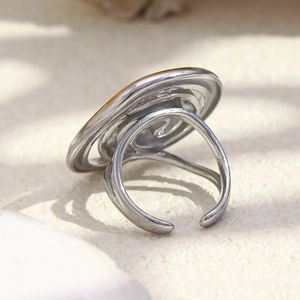 Minimalist silver-tone open spiral ring with circular flat top on textured stone base