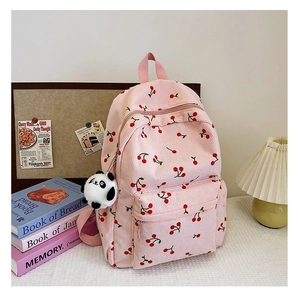 Detail of pink corduroy backpack with cherry pattern and cute panda accessory