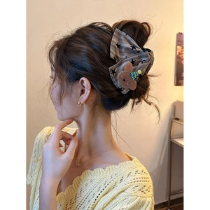 Cute plaid bow bear hair claw clip for women, shown on hair in a cozy indoor setting
