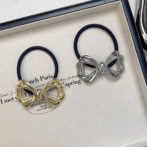 Golden and silver hollow bow hair ties set on a white tray with high elastic bands