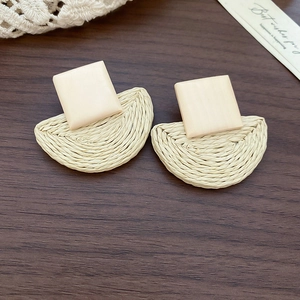 Detailed macro view of bohemian square wood and raffia woven semicircular earrings